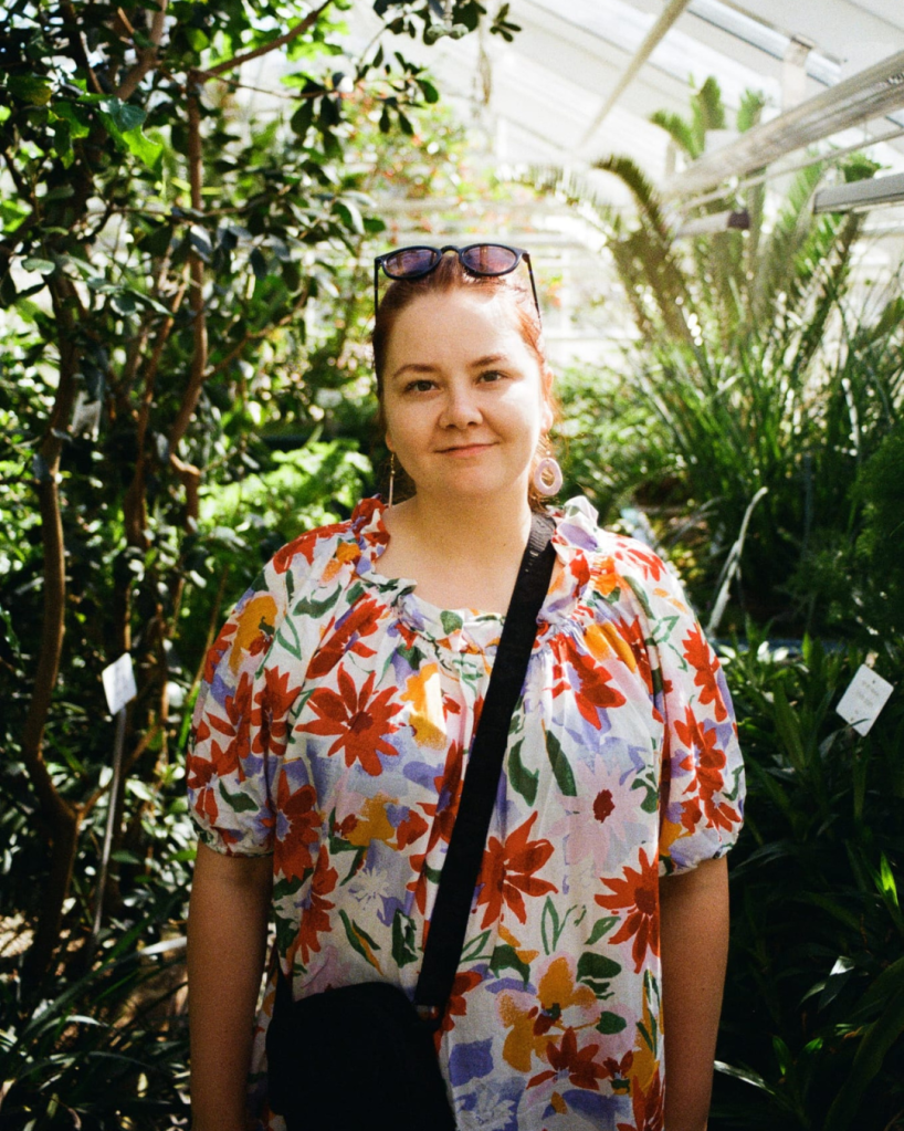 Nainen seisomassa kasvihuoneessa.